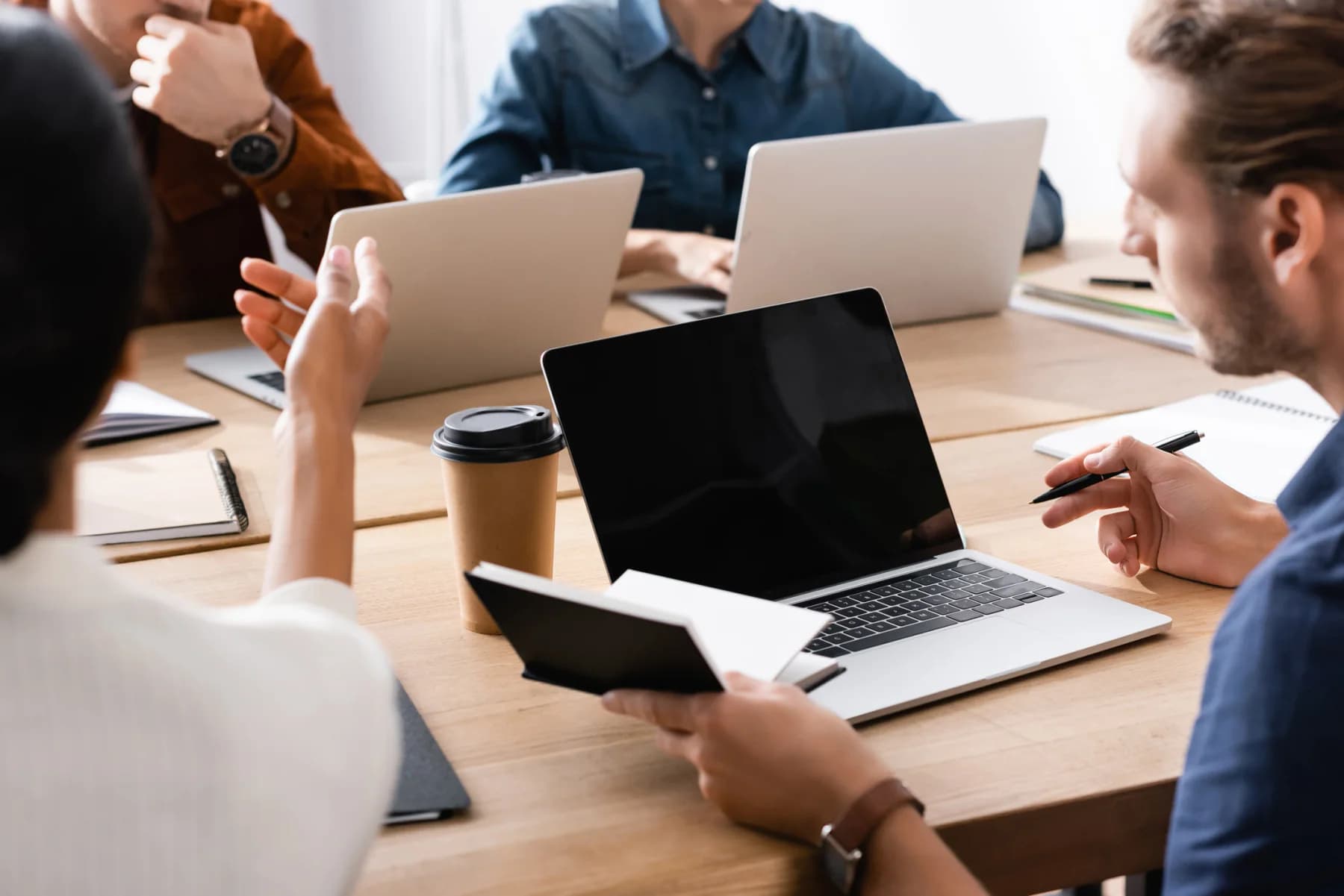 Enterprise project team working in a modern office with laptops and large displays