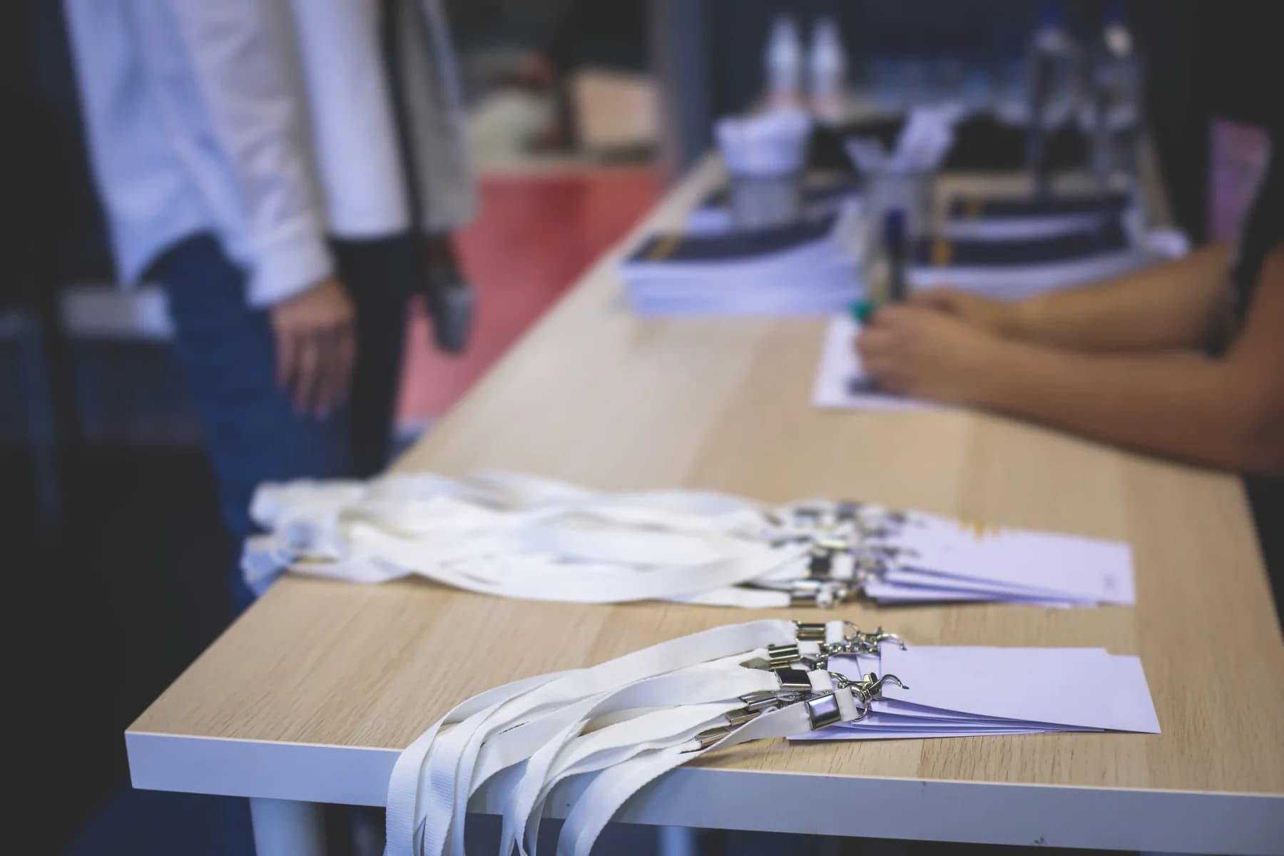 Busy event registration area with tablets, laptops, check-in desks, badge support equipment, and attendees arriving at a conference or trade show