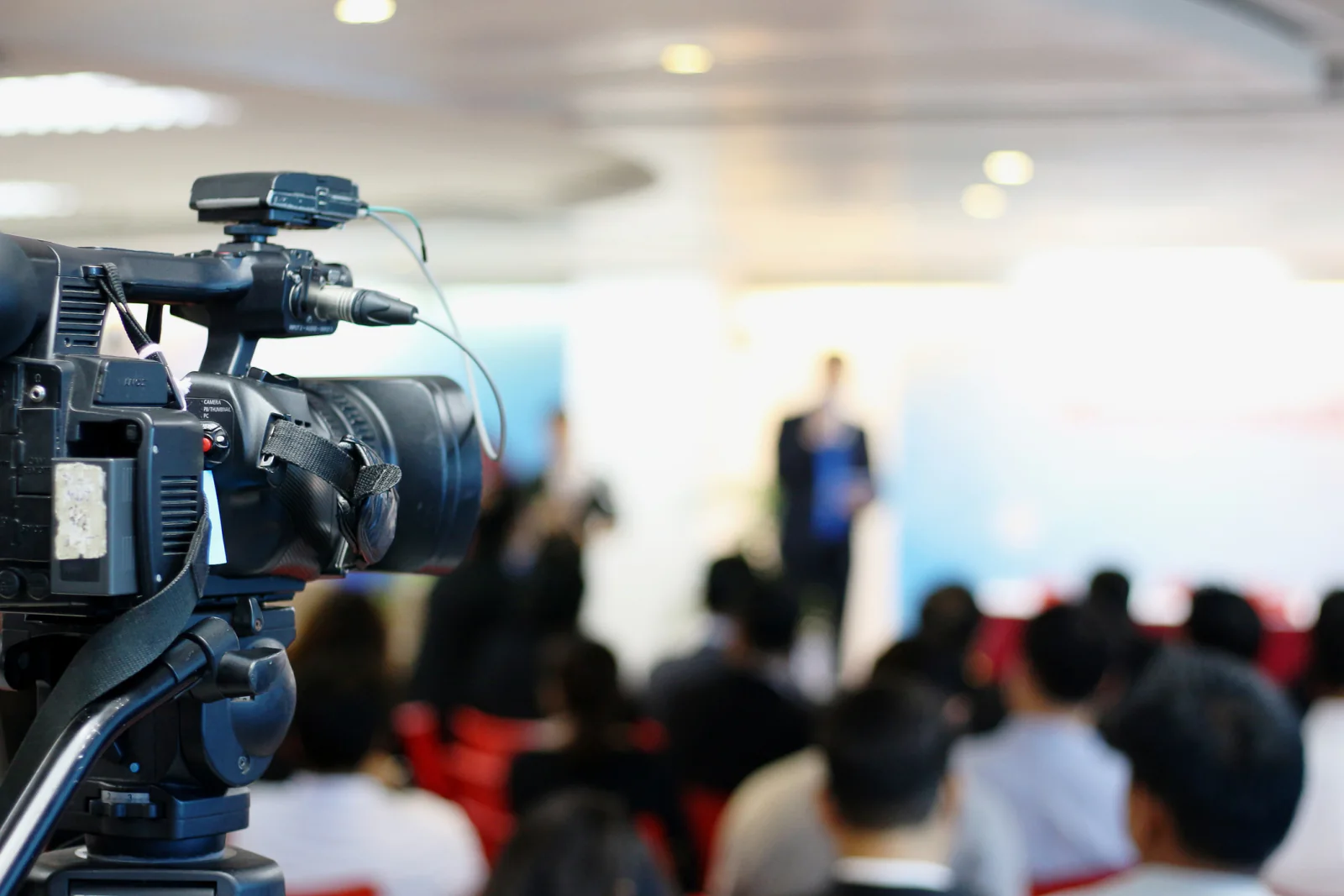 Camera on tripod with streaming and capture equipment recording a live business event or hybrid presentation