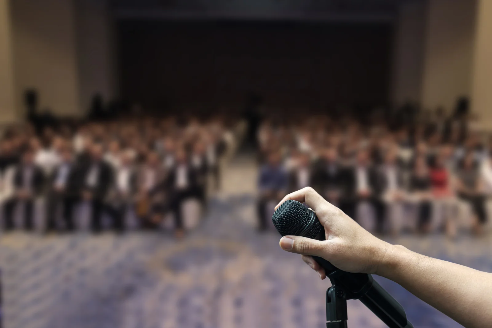 Audience member asking a question with a handheld microphone during a conference or event session