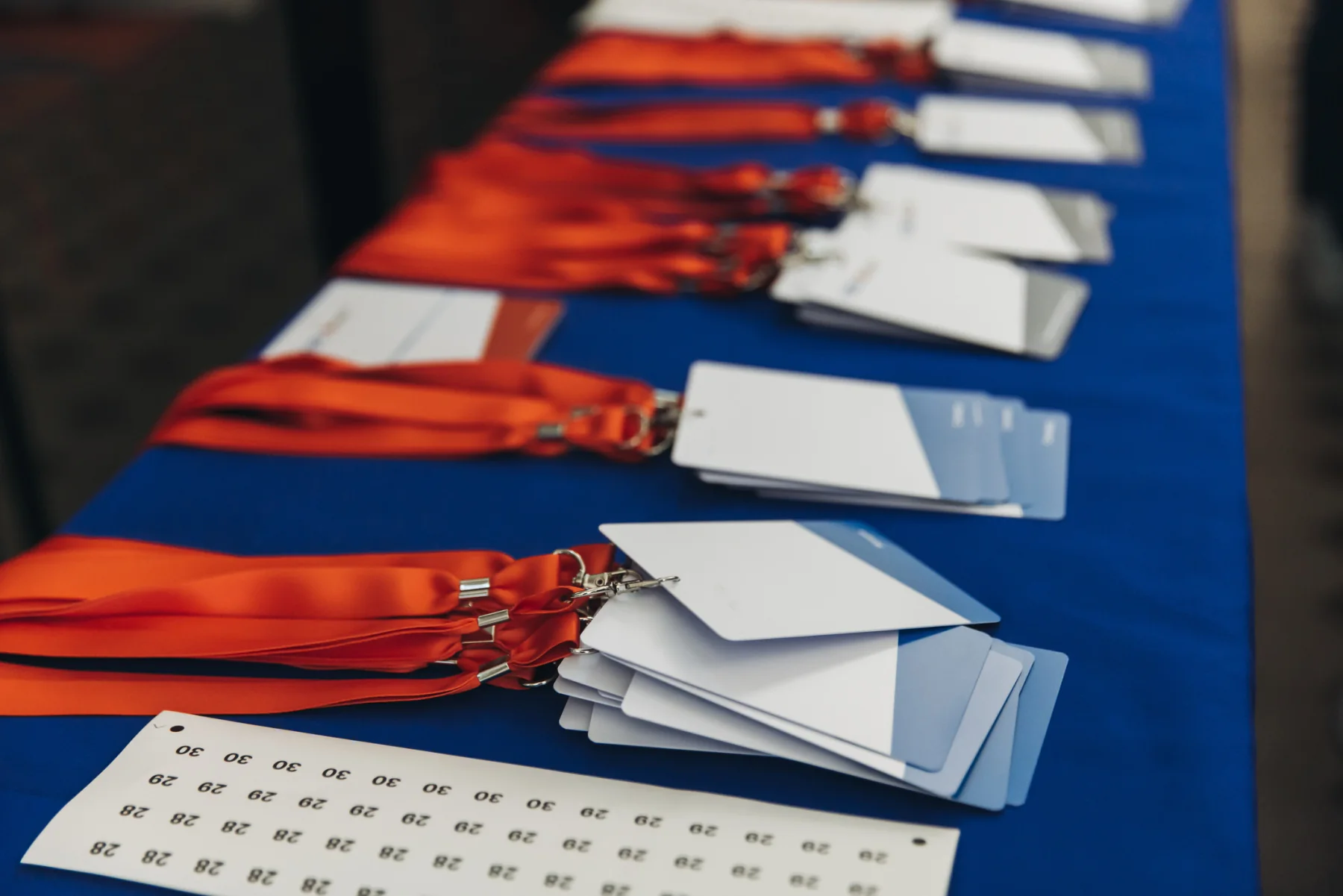 Large multi-day event registration setup with several check-in desks, tablets, laptops, and staff supporting attendee arrivals