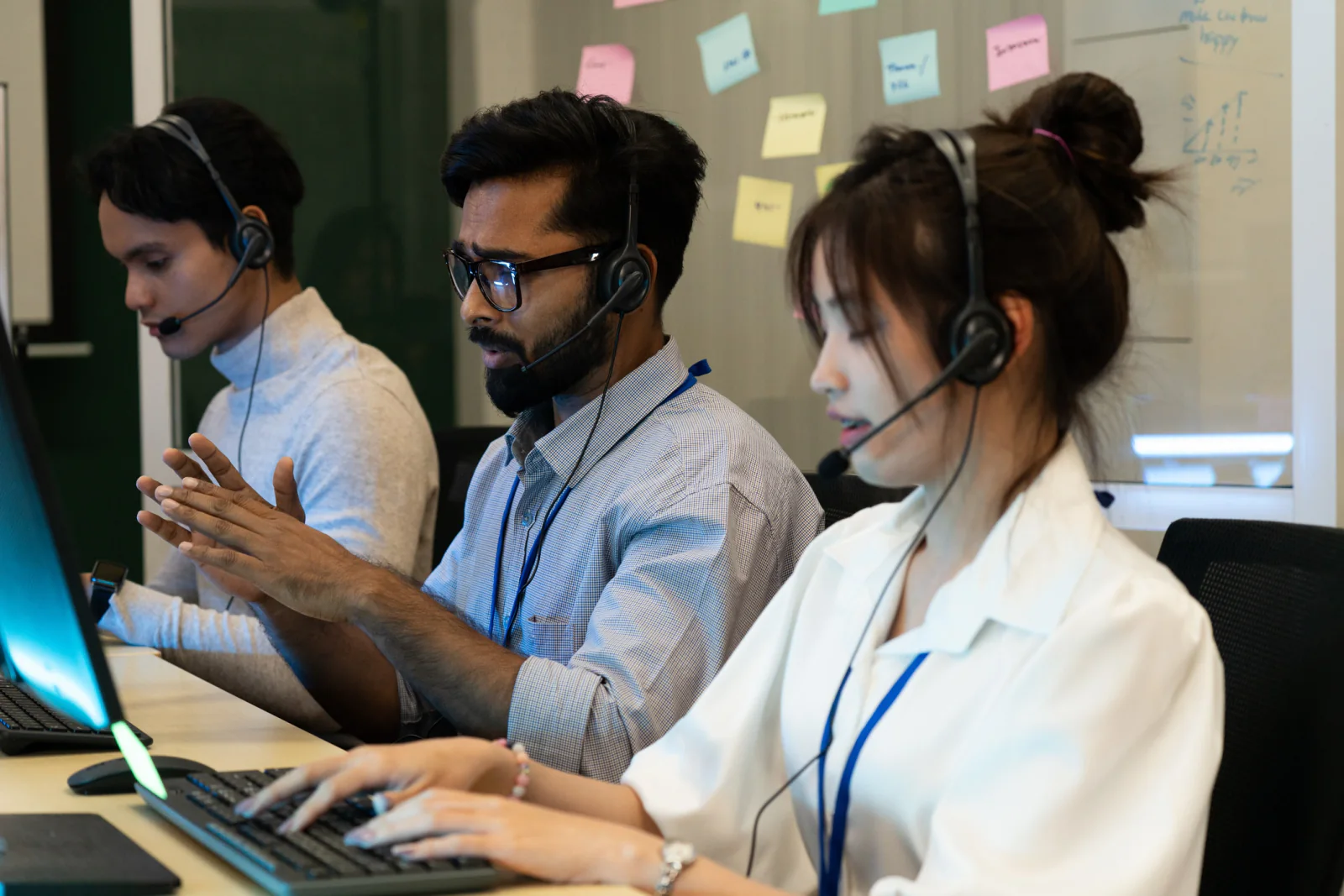 Row of campaign volunteers making calls with headsets and computers in a phone bank