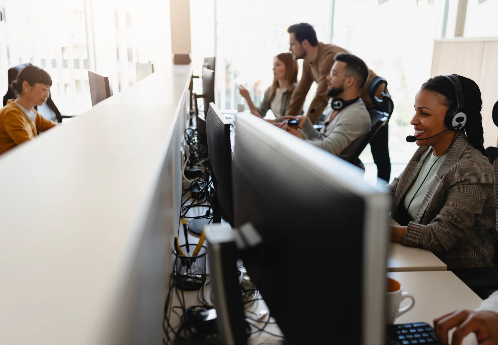 Temporary contact center with rows of dual-monitor workstations, headsets, and enterprise support staff handling customer calls