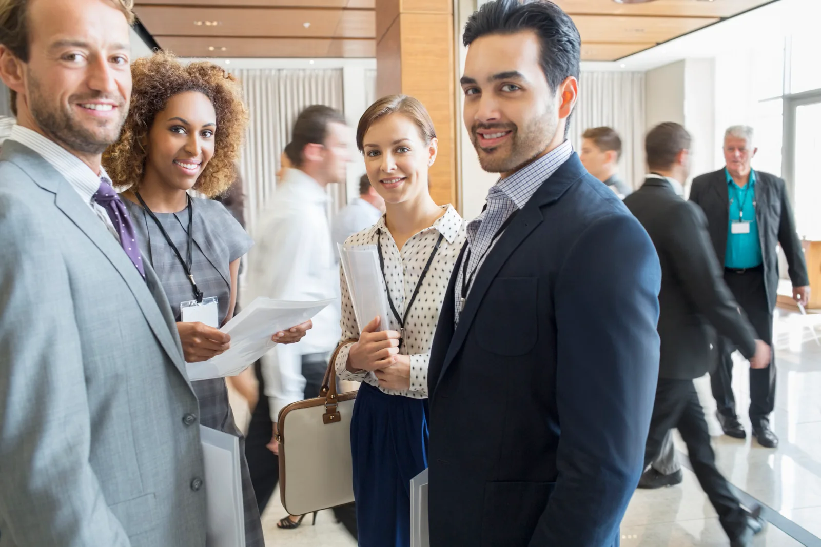 Corporate conference venue with registration technology, large digital displays, branded event signage, and attendees checking in