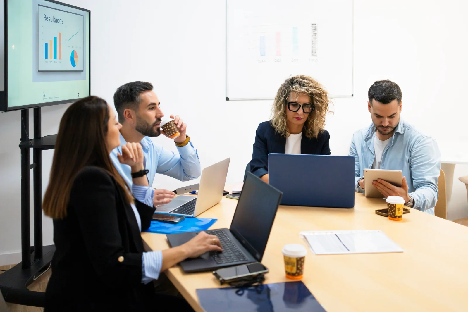 Deal team collaborating around shared screens and laptops in a transaction war room setting