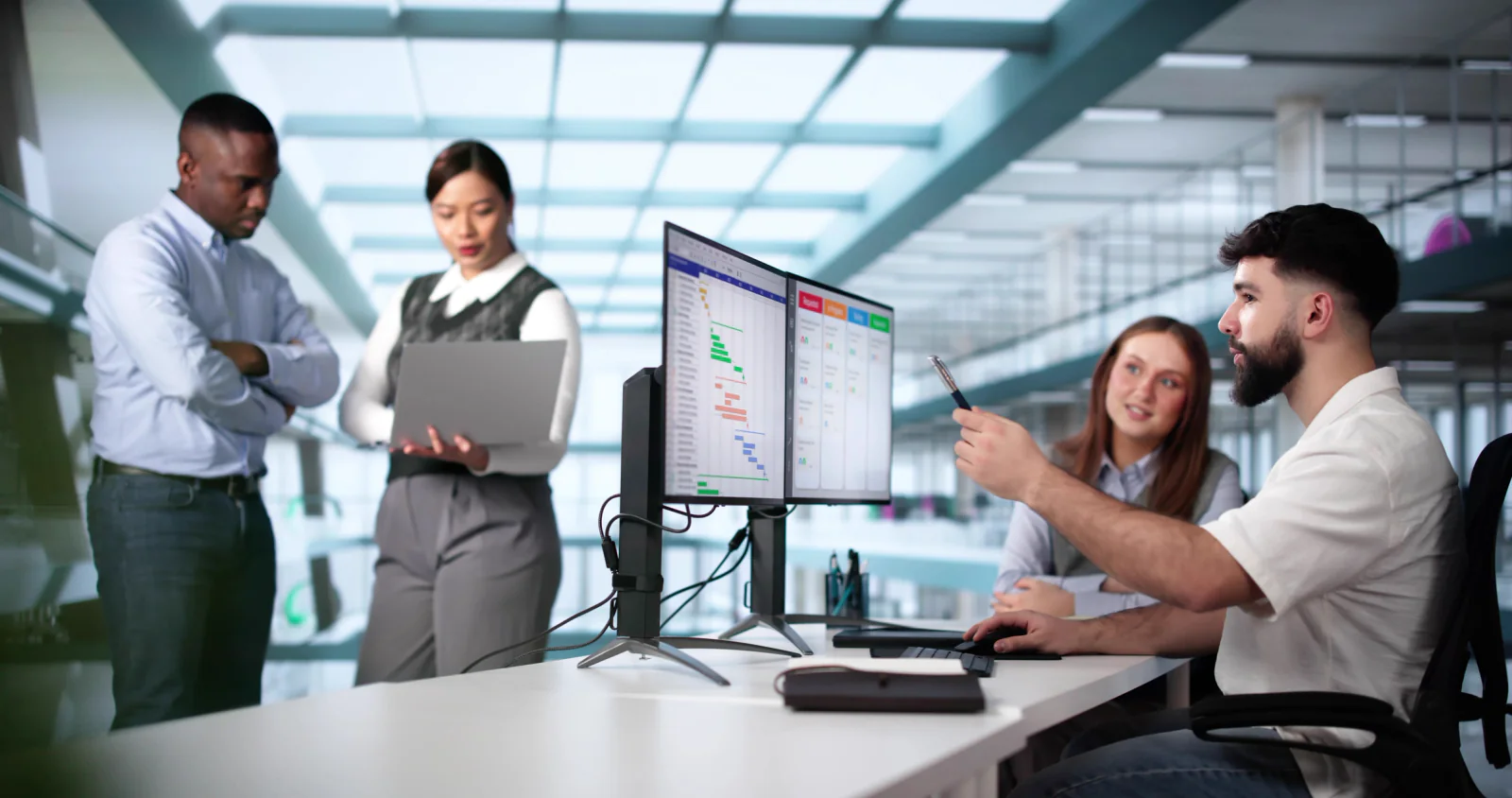 Energy project office with engineers and project managers working at laptops, dual monitors, and collaboration displays during a capital program