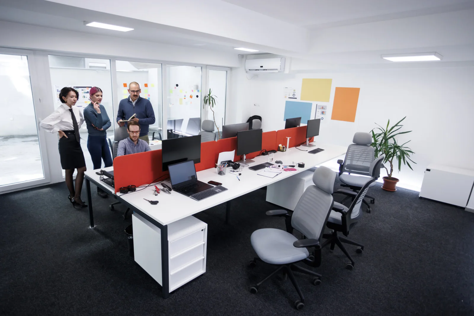 Temporary government office with desks, monitors, laptops, printers, and staff working in a swing space environment