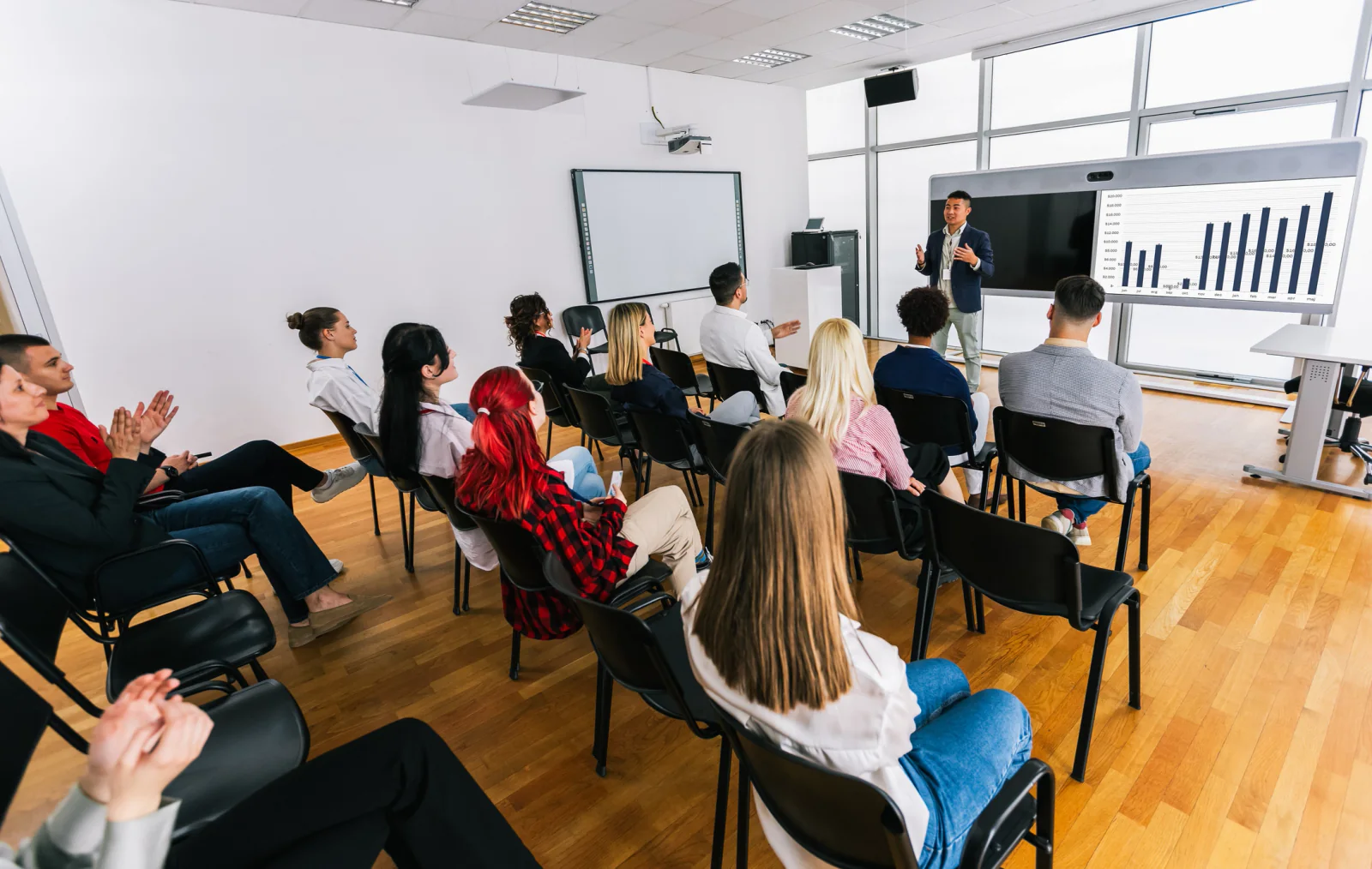 Government employees using laptops in a training room with a projector and screen during an agency learning program
