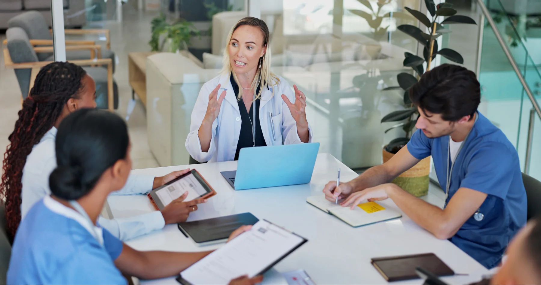 Healthcare professionals using laptops and tablets in a clinic environment