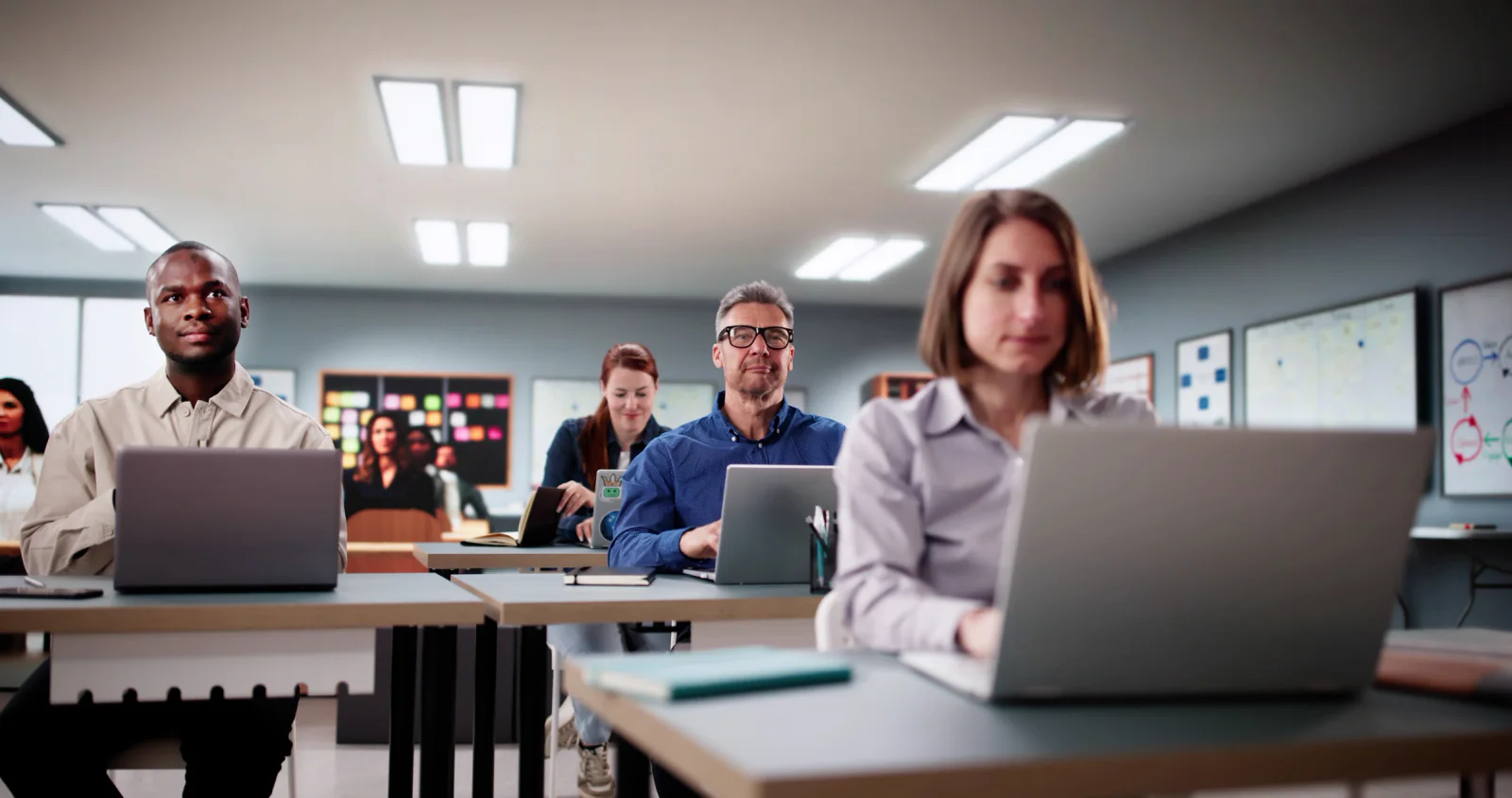 Government training room with employees using laptops, instructor presentation screens, and classroom AV during an agency workshop