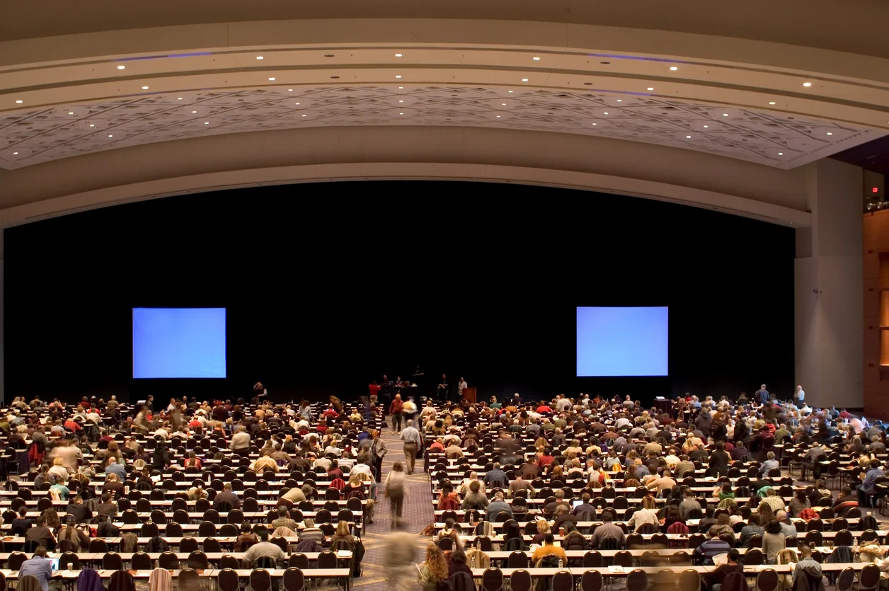Hotel ballroom set for a conference or gala with large presentation screens, stage lighting, and event AV equipment