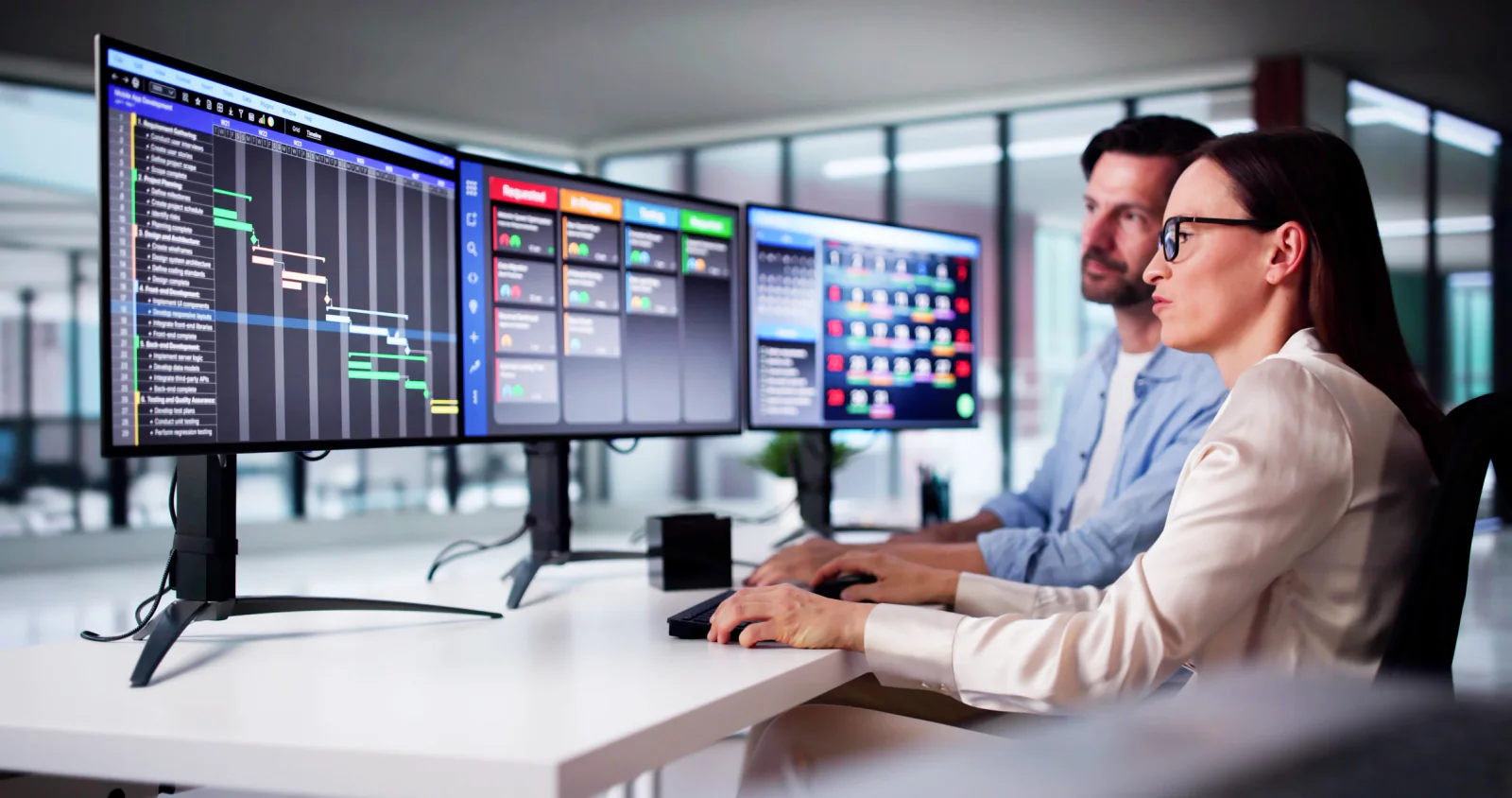 Busy newsroom with staff working at computers and large displays showing live feeds