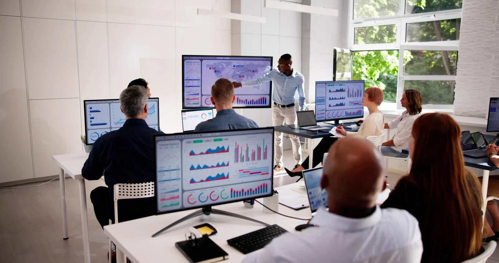 Event command center with meeting planners using dual-monitor workstations, printers, and large planning displays to manage a live program