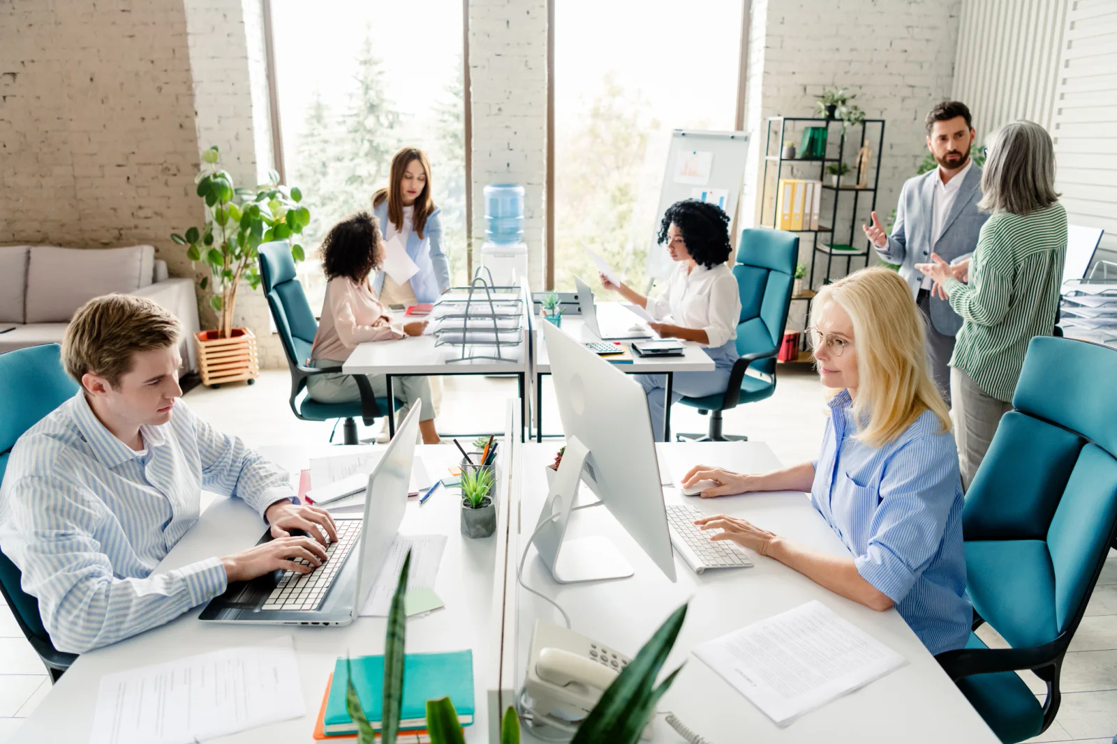Growing small business office with new employee workstations, laptops, dual monitors, and printers set up for an expanding team