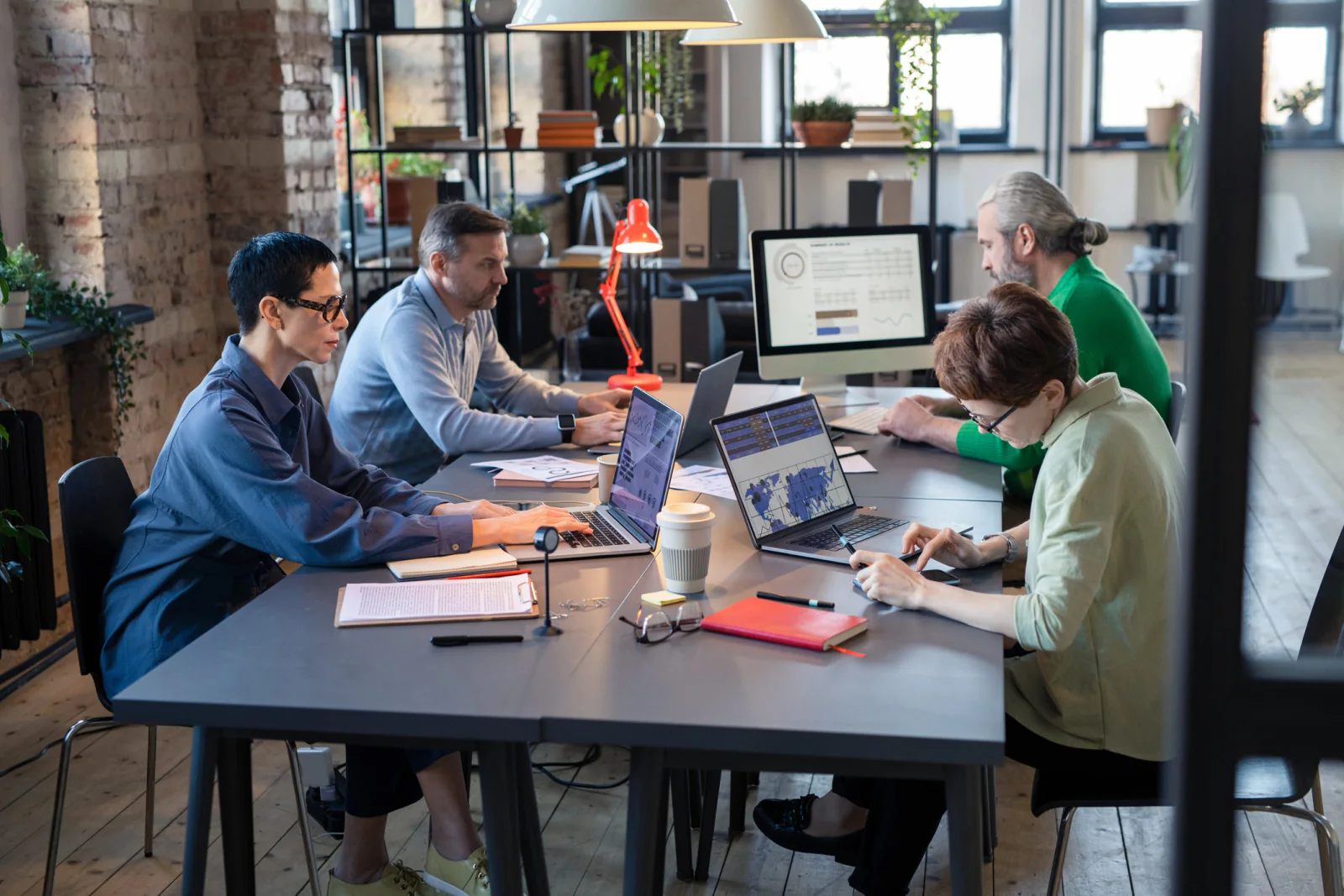 Project team in a temporary business workspace using laptops, a collaboration display, and shared office equipment during an initiative rollout