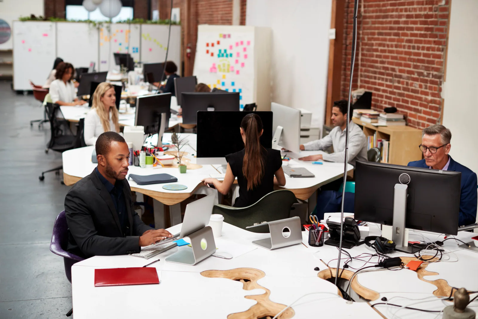 Temporary seasonal staff working at rented laptops and monitors in a busy small business office during a peak period