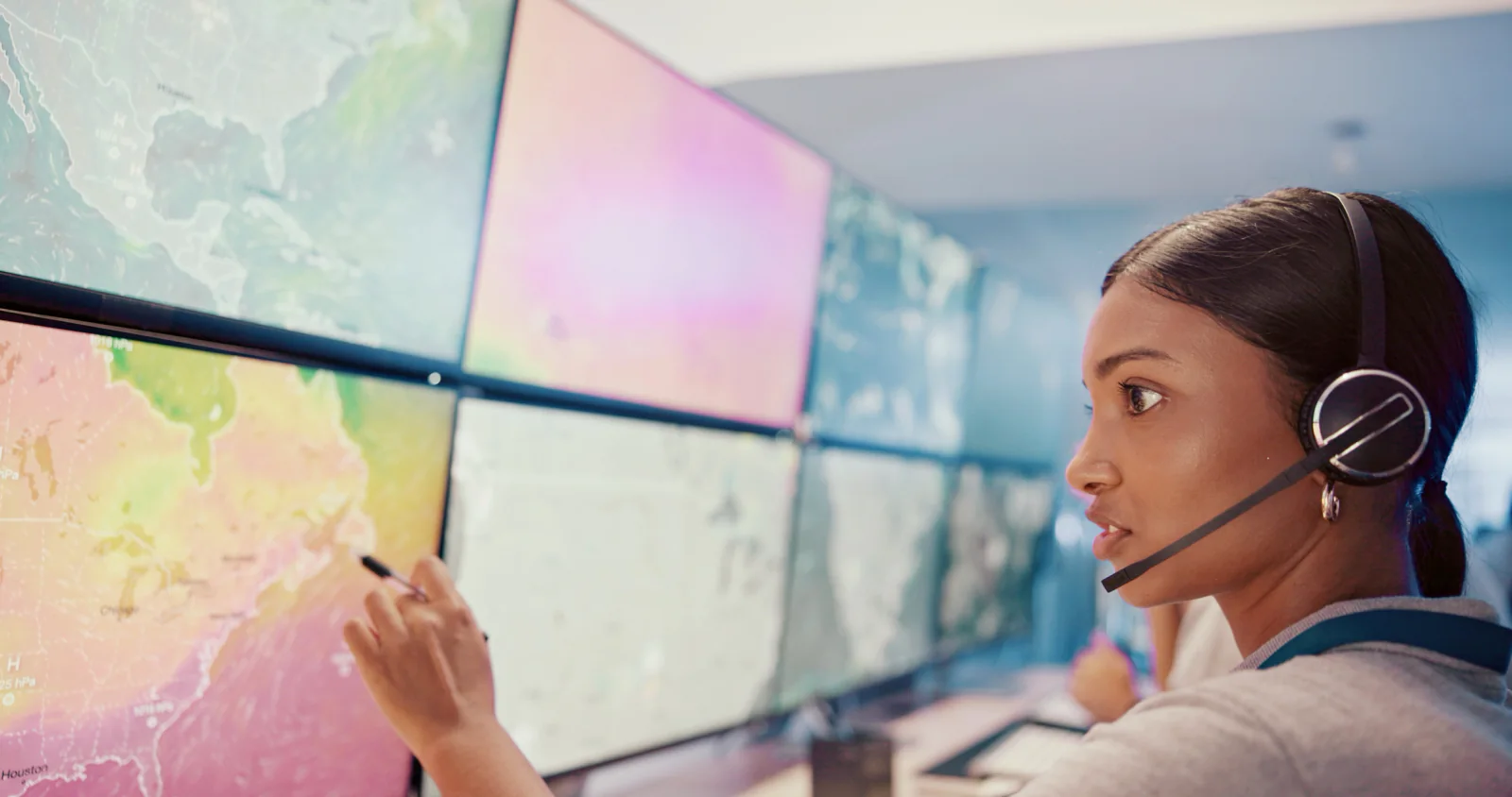 Telecommunications incident command center with staff at multi-monitor workstations and wall displays coordinating restoration efforts
