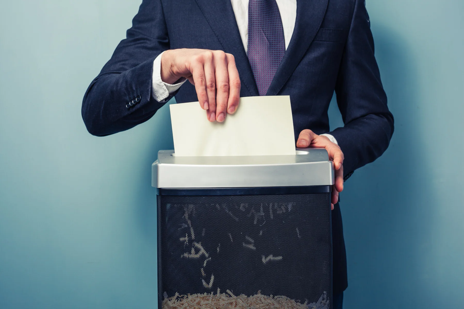 Office worker shredding documents in a shared workspace during a temporary records cleanup project