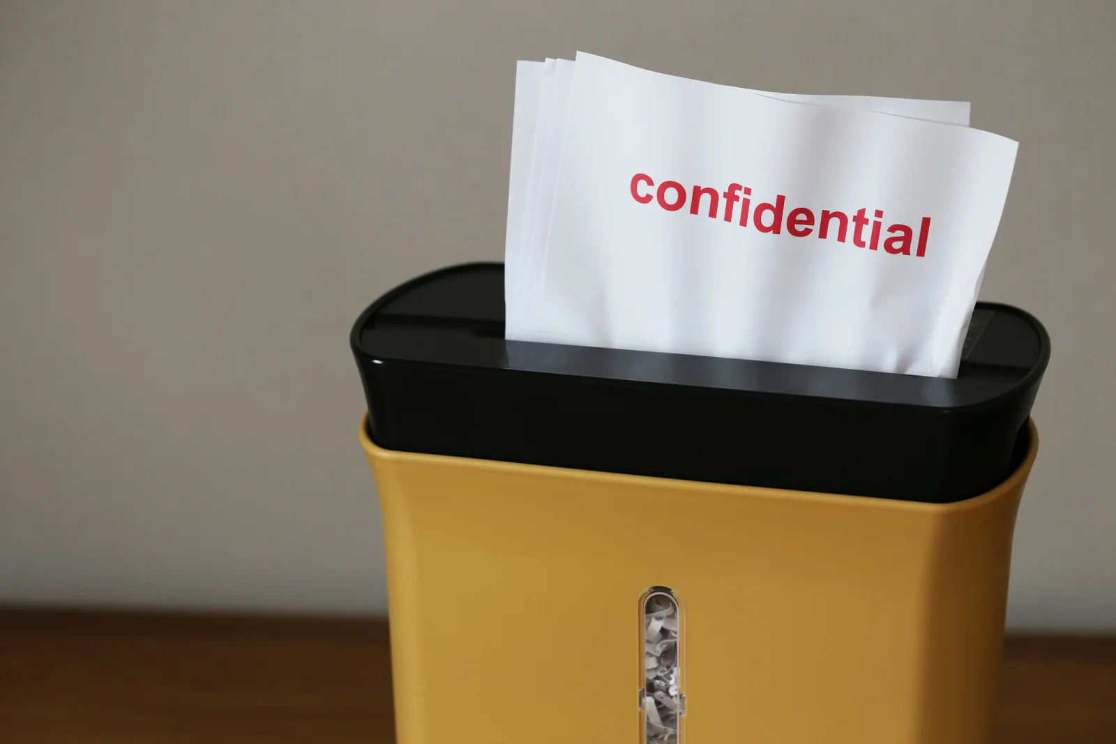 Small office paper shredder next to a desk for secure document disposal during daily business work