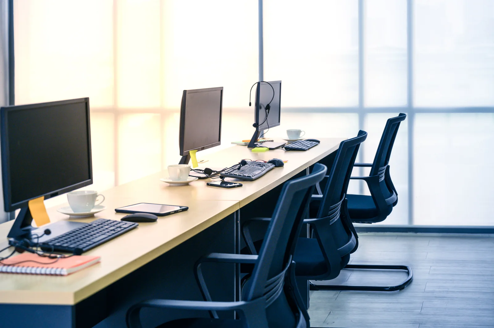 Temporary office desks with monitors, docks, adapters, and peripherals for short-term project room use