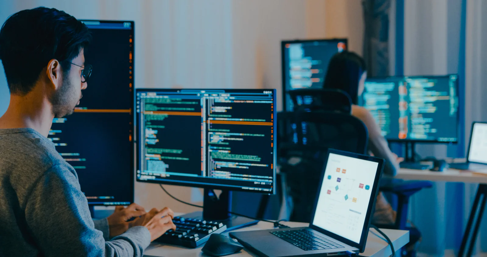 Software engineers benchmarking applications on high-performance laptops and monitors in a structured validation lab
