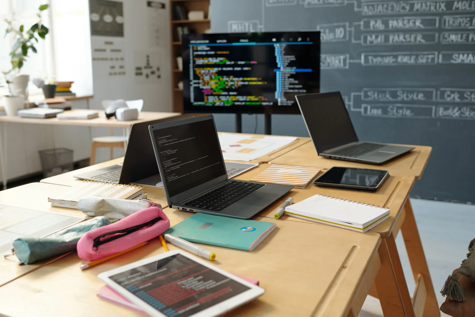 Technical workshop with developers using laptops in a classroom setting with presentation screens and training materials