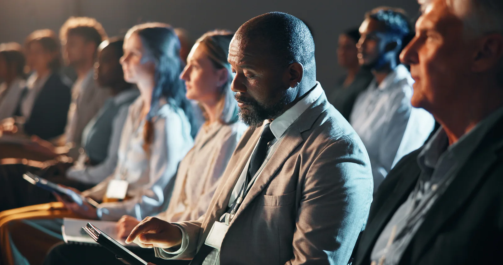 Executive corporate meeting with leadership speakers, presentation displays, and support staff managing a high-visibility session