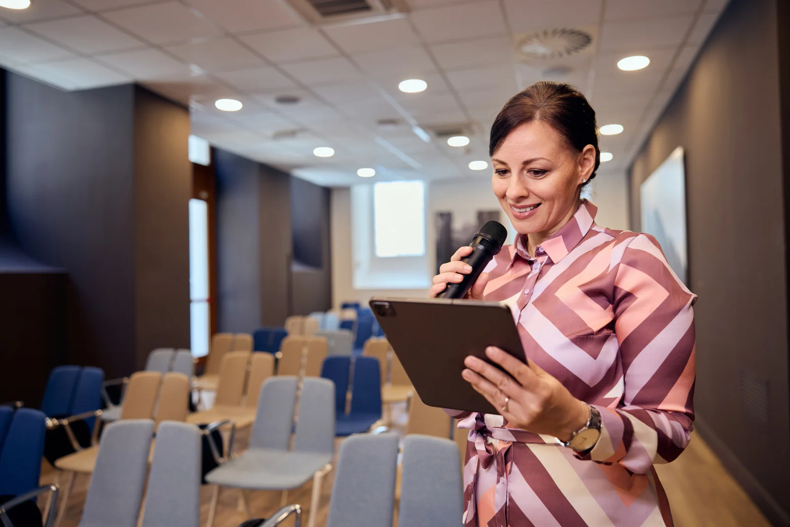 Corporate event presenter support area with laptops, presentation screens, adapters, and staff preparing executive sessions