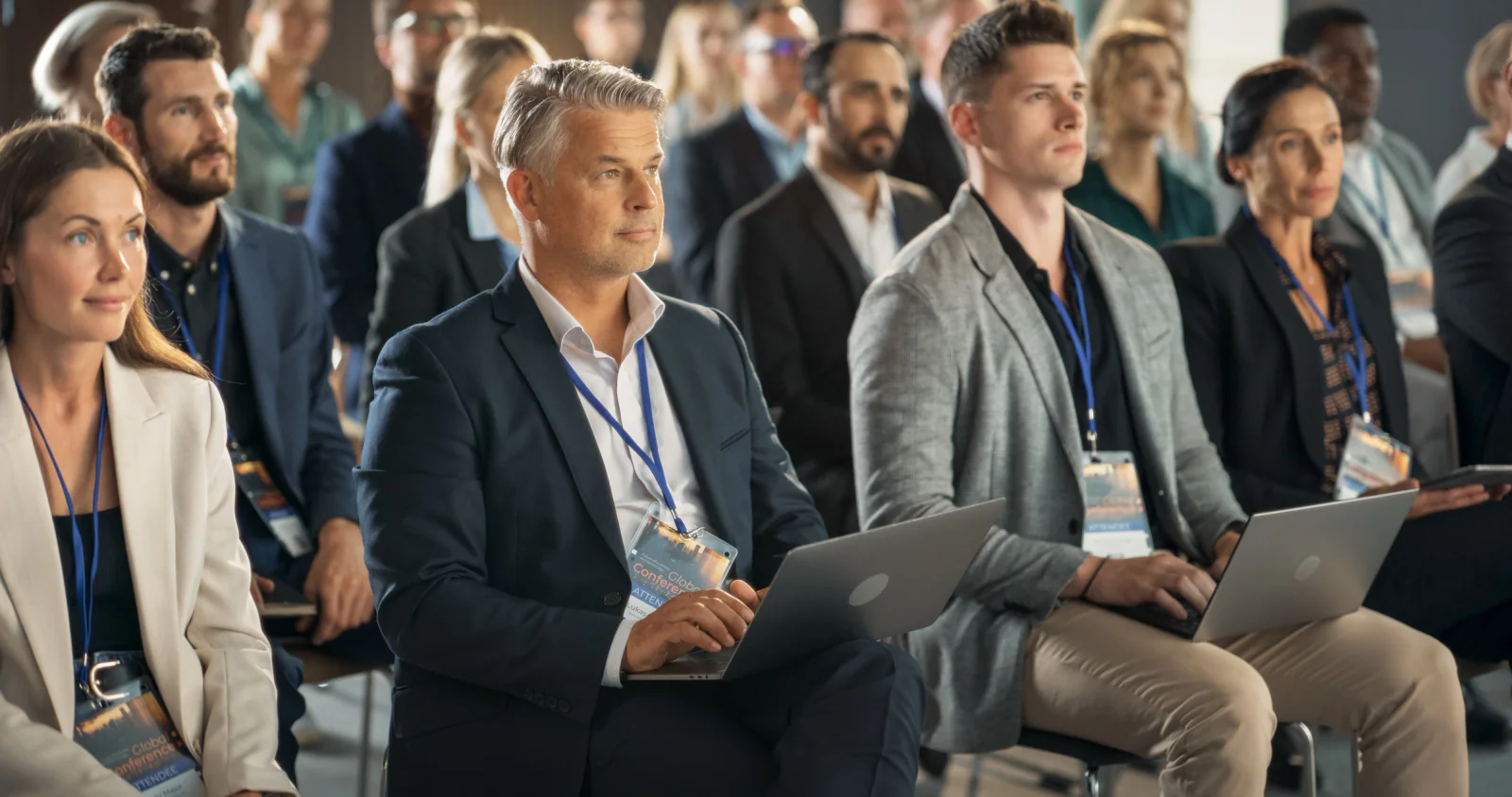 Corporate sales kickoff meeting with presentation screens, attendee seating, and event staff supporting a multi-room business program