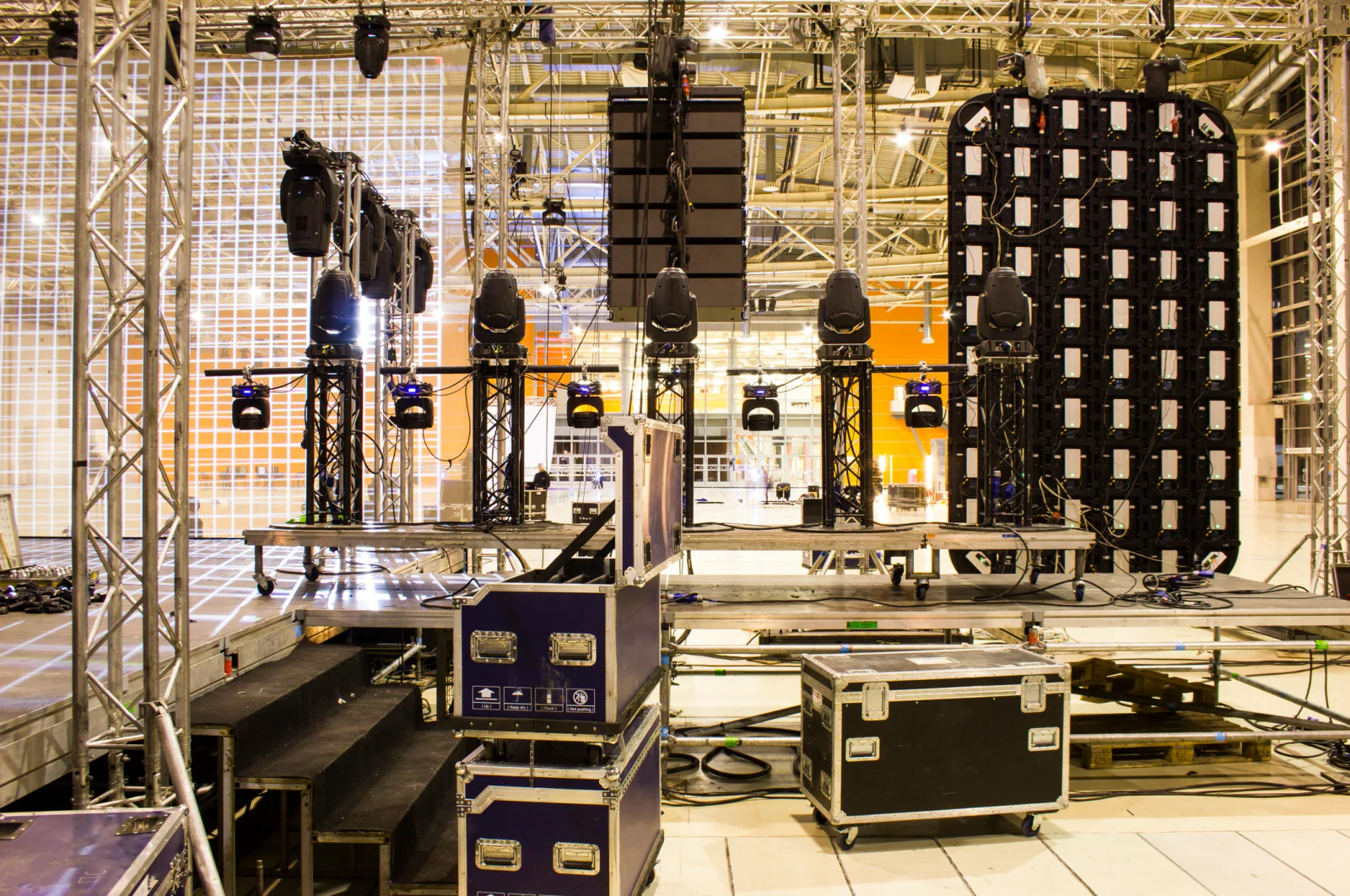 Concert backstage operations area with staff using laptops, tablets, and event support technology during a live show