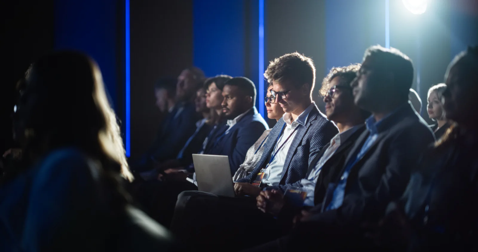 Corporate meeting and breakout event with presentation screens, attendee seating, and staff managing event technology