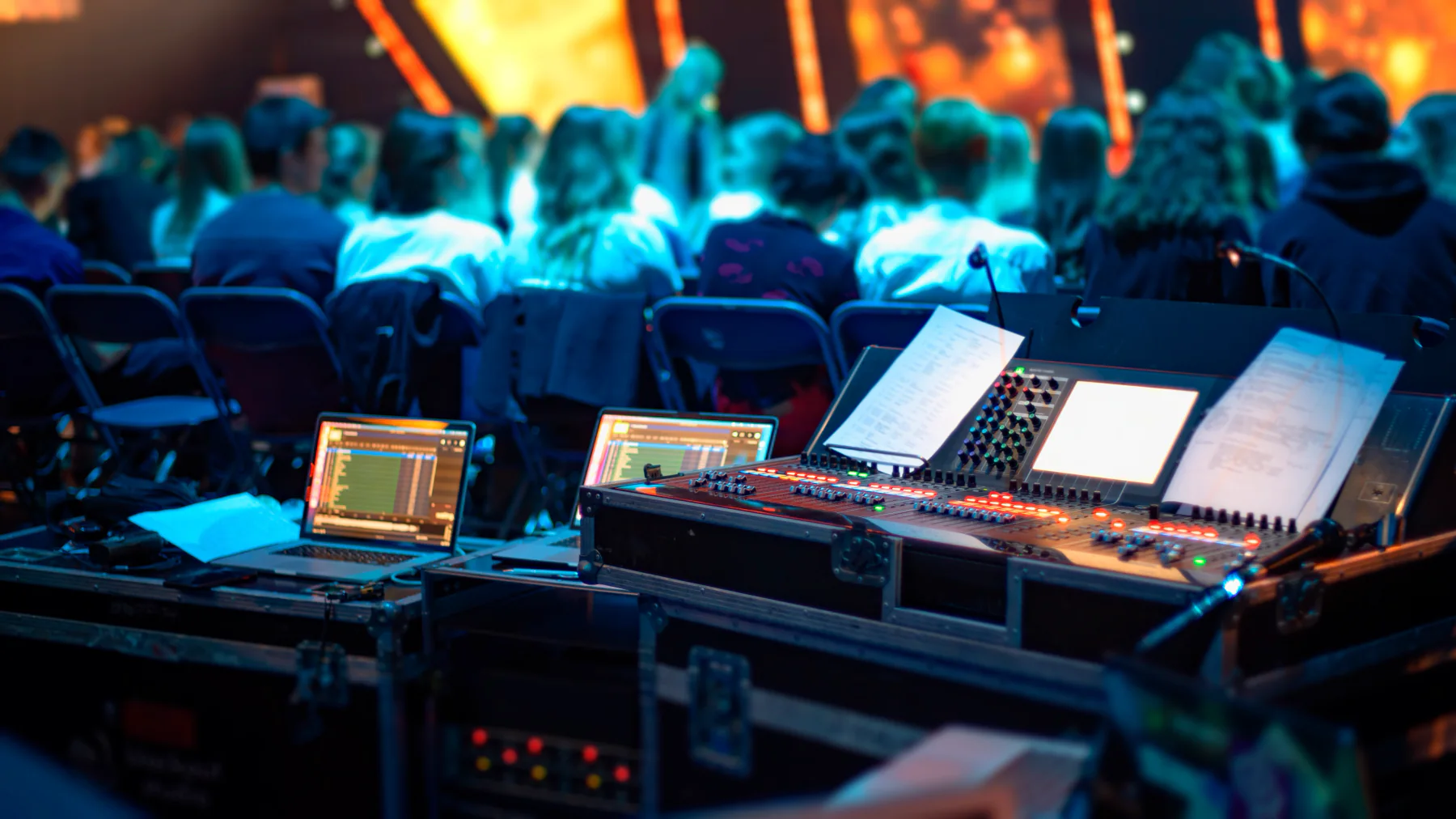 Large event production environment with staging, seating, displays, and staff coordinating technology operations