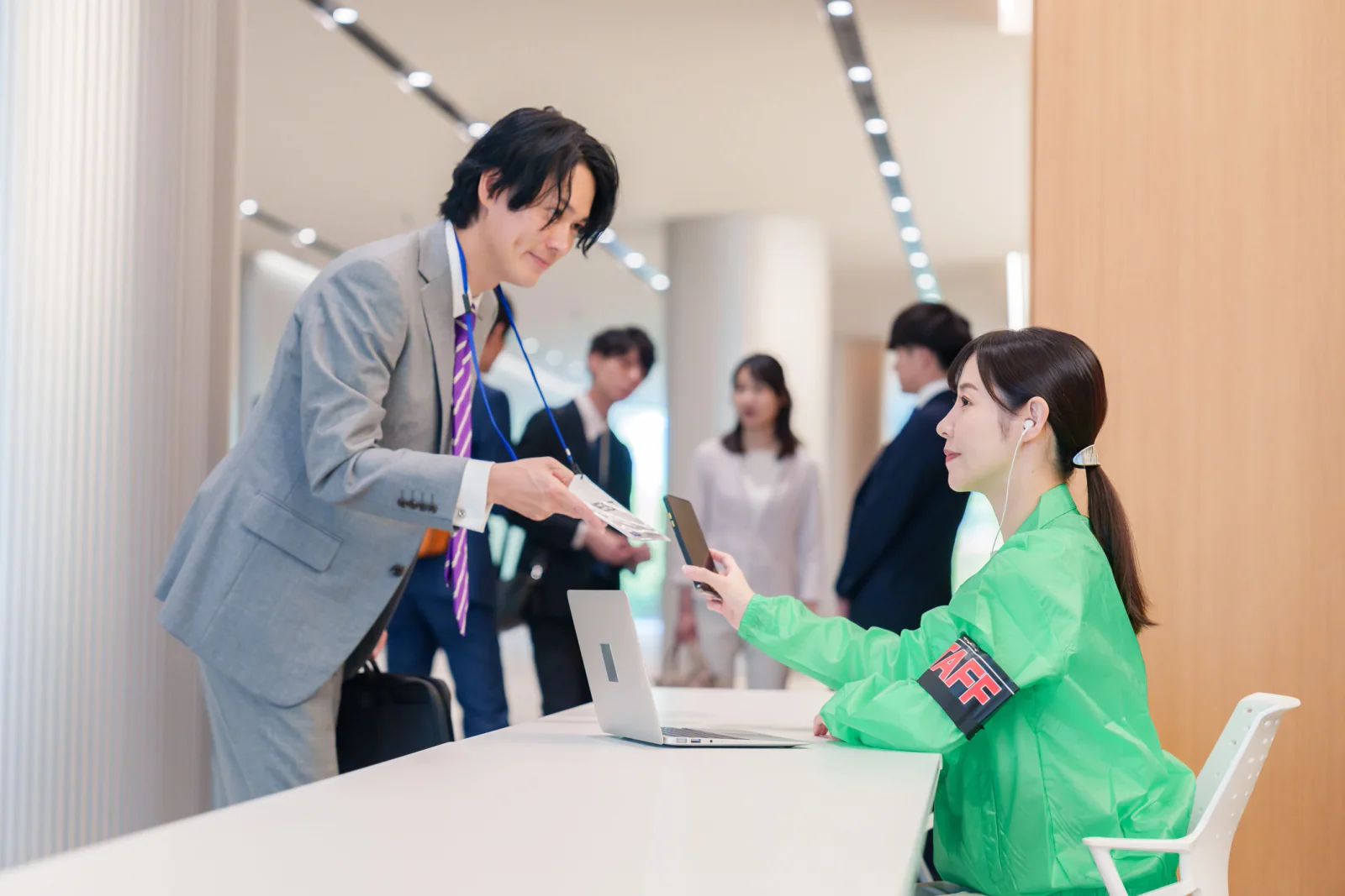 Graduation guest check-in area with staff using tablets, laptops, and event support technology at a high-attendance ceremony venue