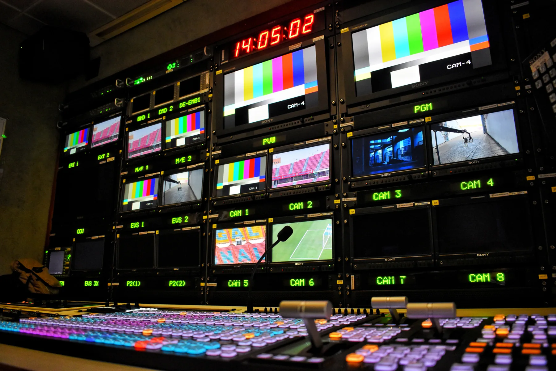 Sporting event operations environment with staff using laptops, tablets, support displays, and credentialing technology at a stadium or arena