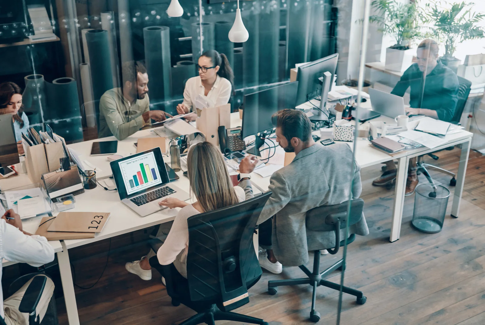 IT rollout coordination team using laptops, project dashboards, and planning documents to manage a technology deployment timeline