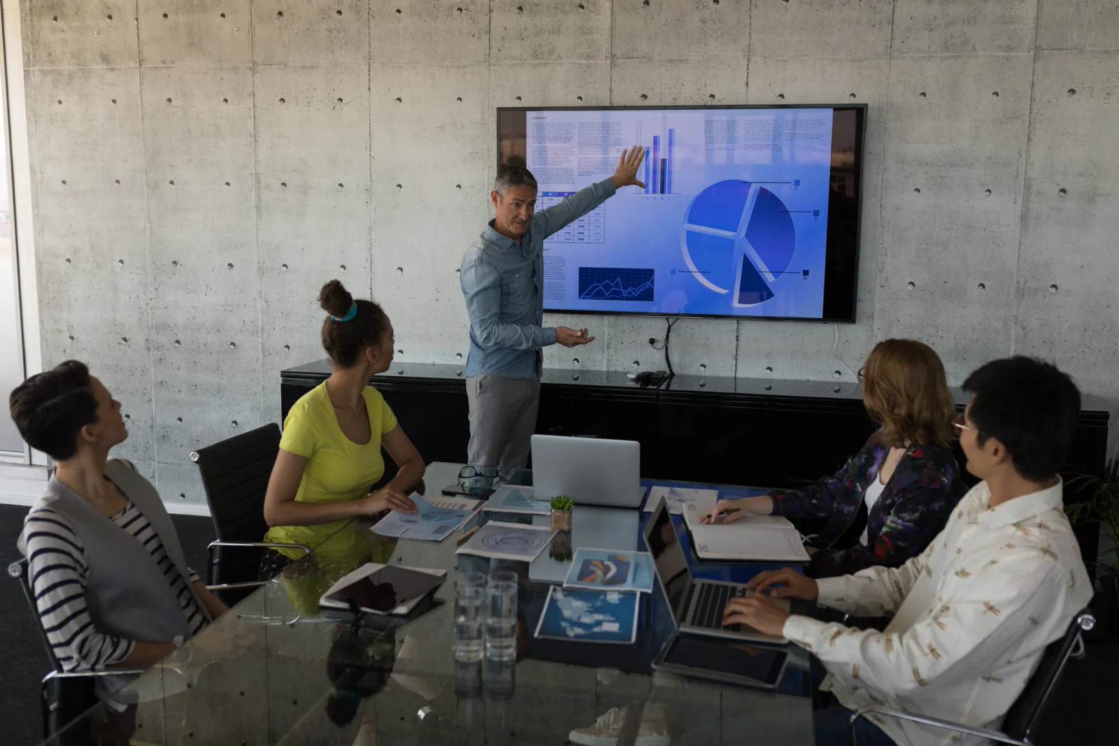 Executive presentation meeting with large display, presenter laptop, conference seating, and polished AV support in a business setting
