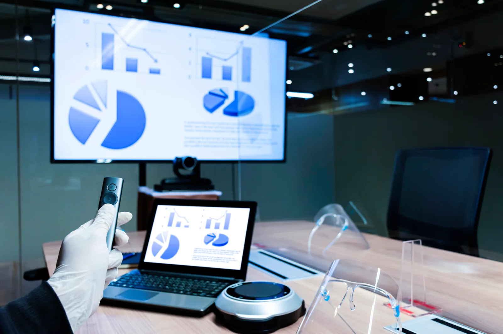 Presenter support area with laptop, adapters, presentation remote, confidence monitor, and staff preparing slides for a live session