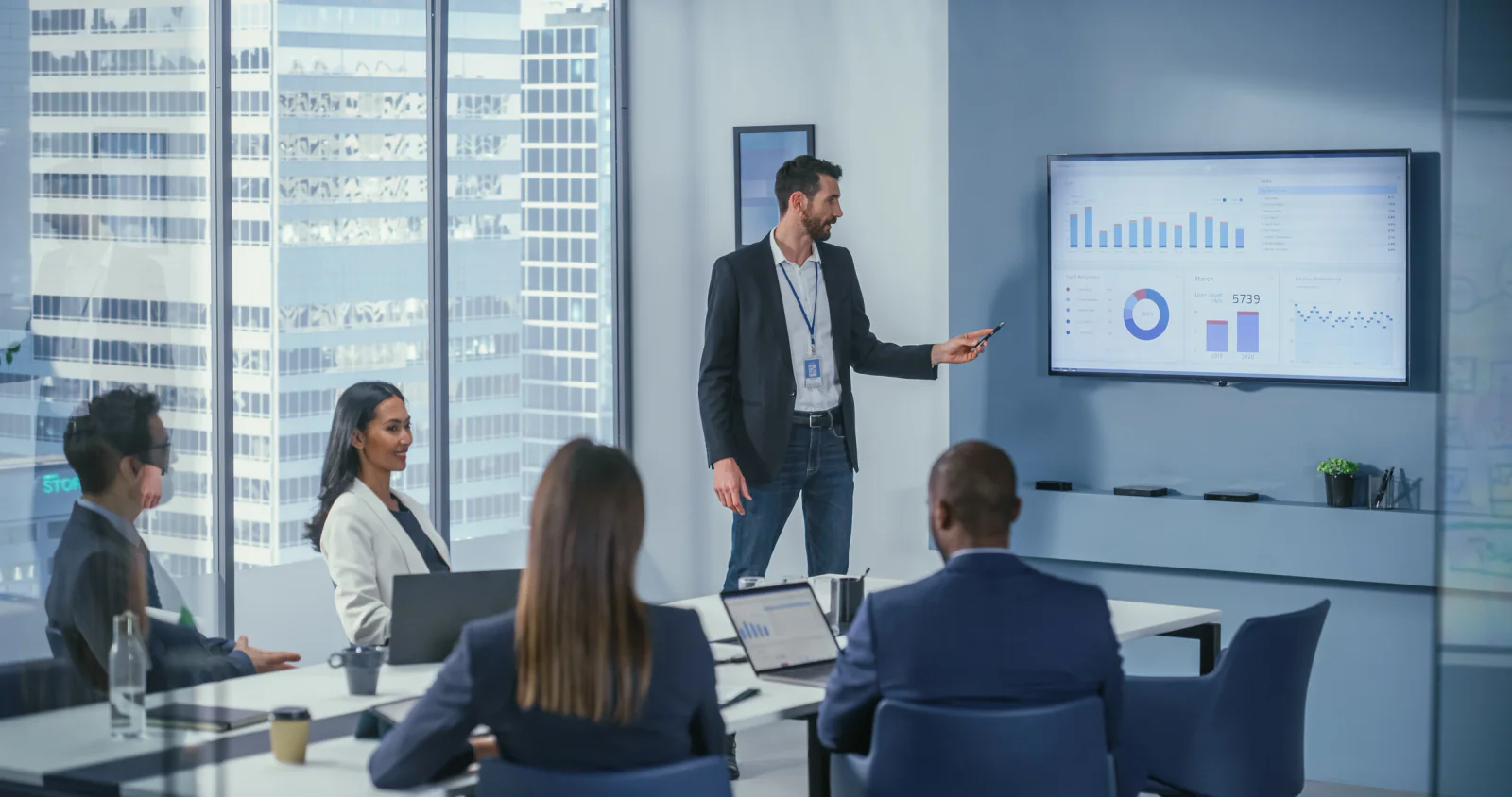 Small business meeting room with flat panel display, presenter laptop, conference table, and presentation equipment ready for use