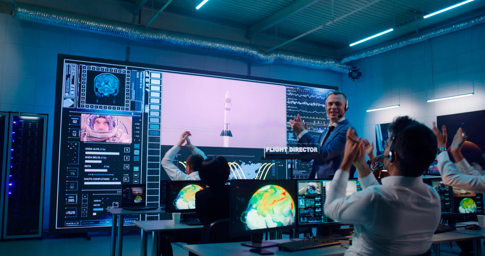Hybrid conference room with stage presentation, streaming workstation, recording support monitors, and mixed in-person and remote audience workflow