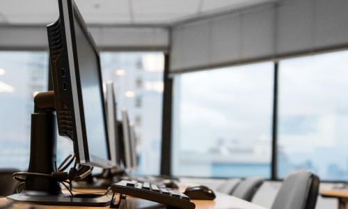 A conference table with desktops, monitors, keyboards, and mice