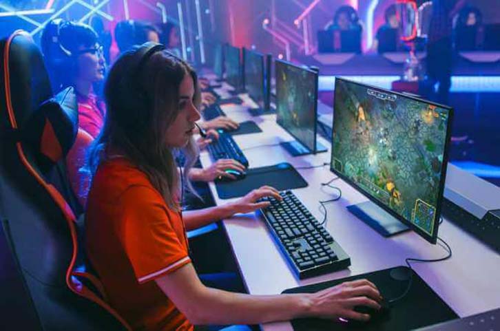 A woman in an orange suit using a high-tech gaming computer in a MOBA 