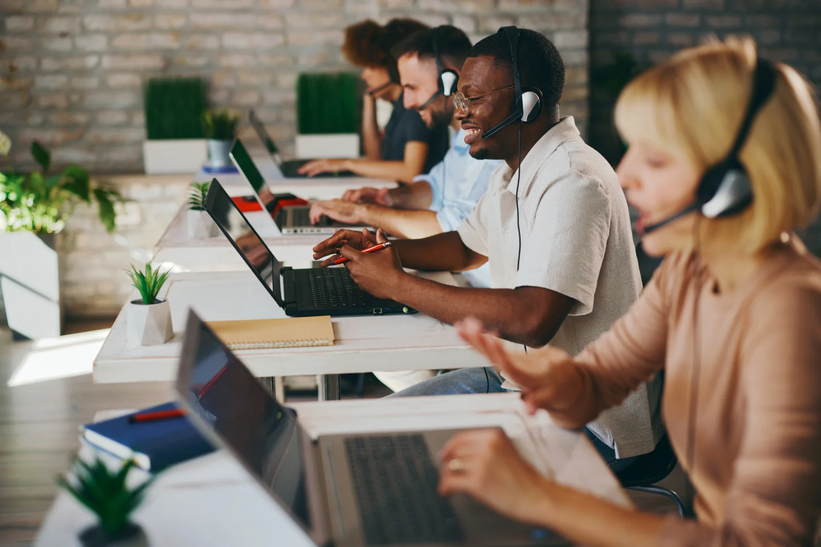 Support desk team using laptops, headsets, and cloud communication tools in a service-focused office environment