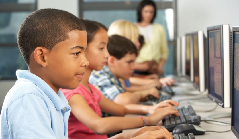 A group of children each typing at a computer